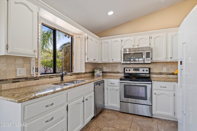 kitchen with appliances with stainless steel finishes, lofted ceiling, sink, white cabinets, and light stone countertops