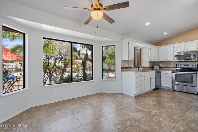 kitchen featuring white cabinetry, light stone counters, stainless steel appliances, and decorative backsplash