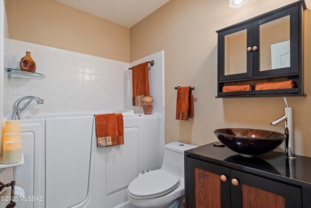 bathroom featuring vanity, a washtub, and toilet