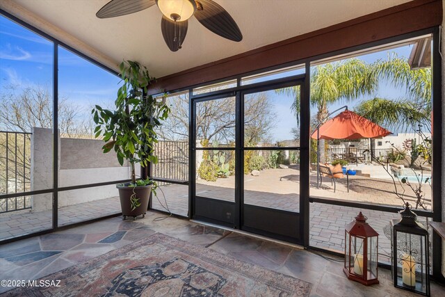 unfurnished sunroom featuring ceiling fan and a healthy amount of sunlight