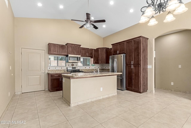 kitchen with appliances with stainless steel finishes, backsplash, a kitchen island with sink, light tile patterned flooring, and high vaulted ceiling