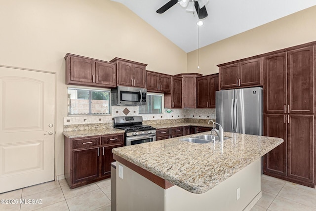 kitchen with appliances with stainless steel finishes, decorative backsplash, sink, high vaulted ceiling, and a center island with sink