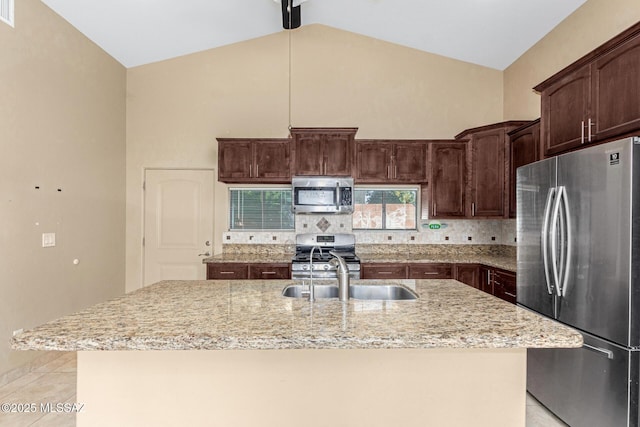 kitchen featuring appliances with stainless steel finishes, sink, high vaulted ceiling, and an island with sink