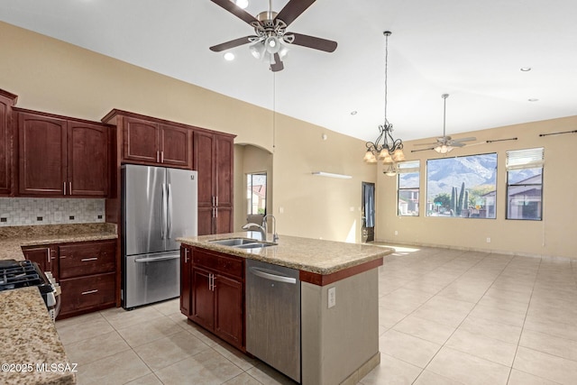 kitchen with decorative light fixtures, backsplash, sink, a kitchen island with sink, and appliances with stainless steel finishes