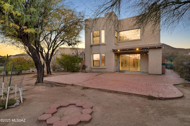 back house at dusk with a patio area