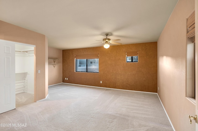 unfurnished bedroom with ceiling fan, light colored carpet, and a walk in closet