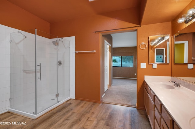 bathroom featuring hardwood / wood-style flooring, vanity, and a shower with door