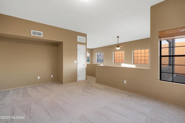 spare room featuring plenty of natural light, light colored carpet, lofted ceiling, and ceiling fan