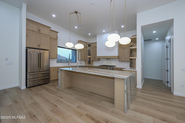 kitchen with decorative light fixtures, sink, light stone countertops, a center island with sink, and high end appliances