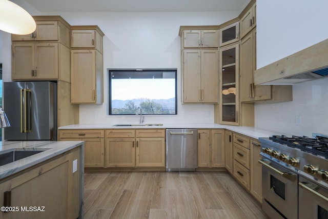 kitchen with high quality appliances, light brown cabinets, sink, and light hardwood / wood-style flooring