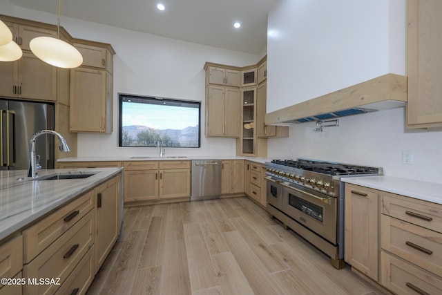 kitchen featuring premium appliances, pendant lighting, light brown cabinetry, custom exhaust hood, and sink