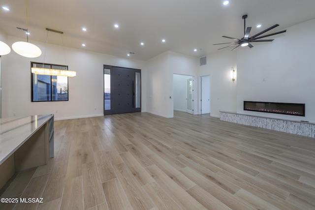 unfurnished living room featuring light hardwood / wood-style flooring and ceiling fan