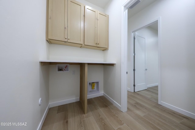 washroom featuring washer hookup, light hardwood / wood-style floors, and cabinets