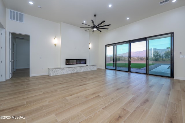 unfurnished living room with light wood-type flooring and ceiling fan