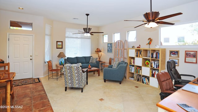 living area with tile patterned flooring, visible vents, and ceiling fan