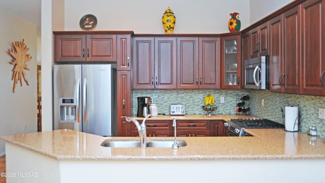 kitchen with tasteful backsplash, stainless steel appliances, kitchen peninsula, and sink