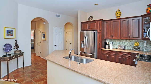 kitchen featuring sink, dark tile patterned floors, range, stainless steel fridge with ice dispenser, and decorative backsplash