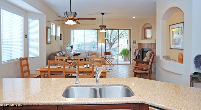 kitchen with a tiled fireplace, a healthy amount of sunlight, sink, and pendant lighting