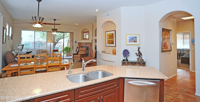 kitchen featuring visible vents, a sink, light tile patterned floors, arched walkways, and stainless steel dishwasher