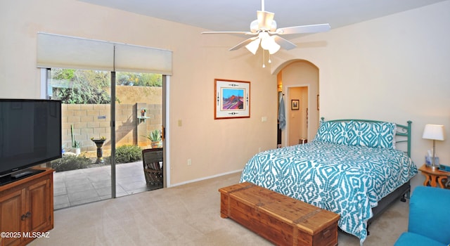 bedroom with baseboards, arched walkways, ceiling fan, access to exterior, and light colored carpet