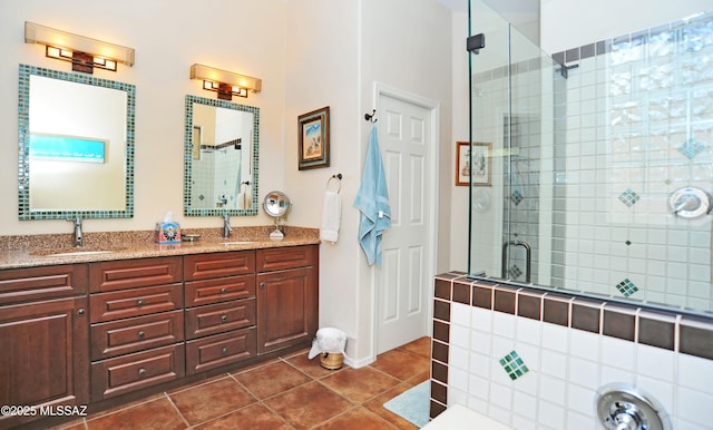 bathroom featuring tile patterned flooring, double vanity, a stall shower, and a sink