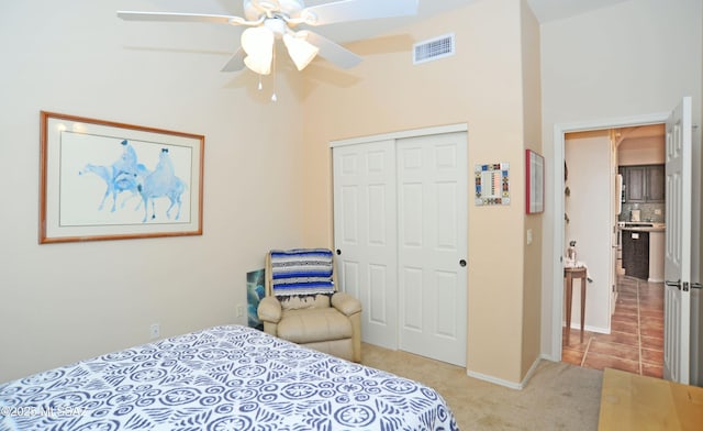 bedroom with tile patterned floors, visible vents, a ceiling fan, a closet, and carpet floors