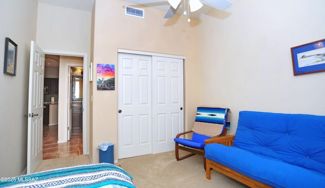 carpeted bedroom featuring visible vents, a closet, and ceiling fan