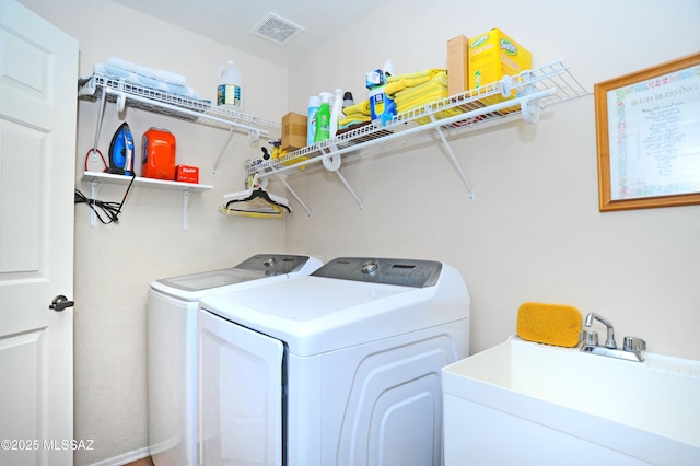 laundry area with a sink, visible vents, laundry area, and washer and clothes dryer