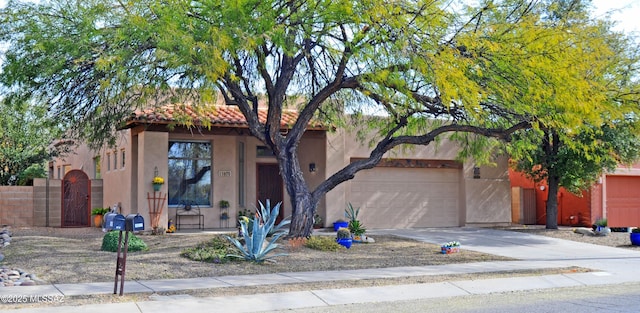 pueblo revival-style home featuring a gate, stucco siding, concrete driveway, a garage, and a tile roof