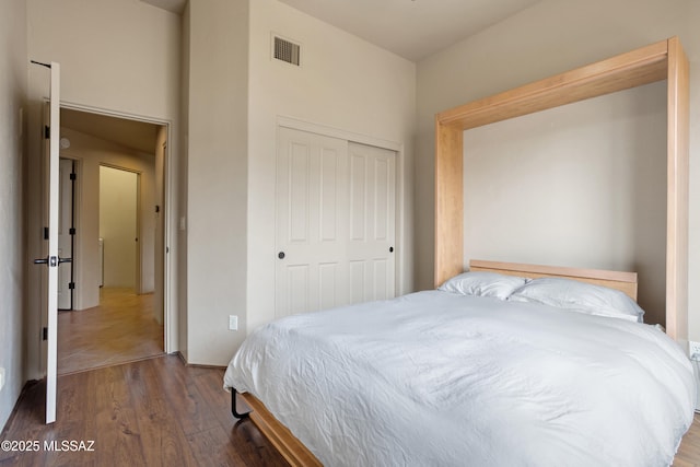 bedroom featuring wood finished floors, visible vents, and a closet