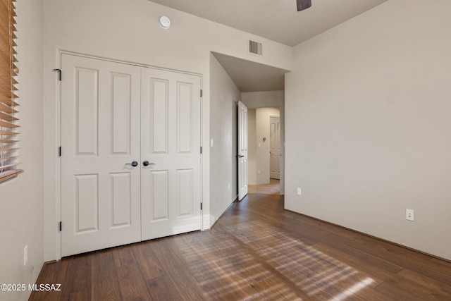 unfurnished bedroom featuring a closet, visible vents, and dark wood-style flooring