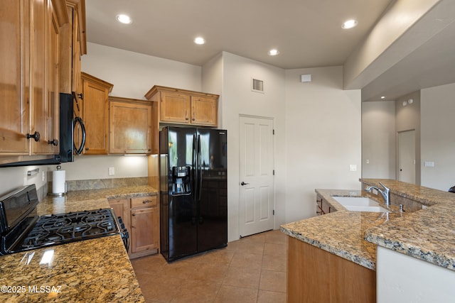 kitchen featuring light stone counters, light tile patterned flooring, sink, and black appliances