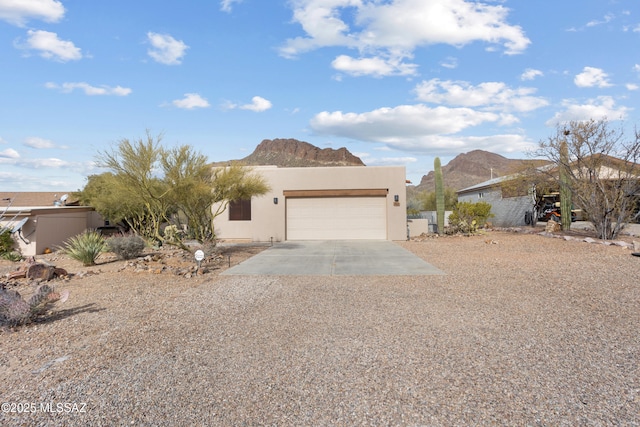 view of front facade featuring stucco siding, an attached garage, driveway, and a mountain view
