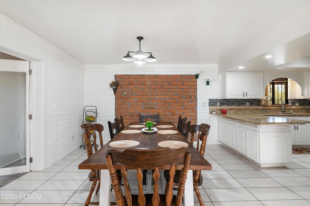 tiled dining area featuring brick wall