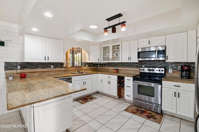 kitchen with a raised ceiling, kitchen peninsula, white cabinets, and appliances with stainless steel finishes