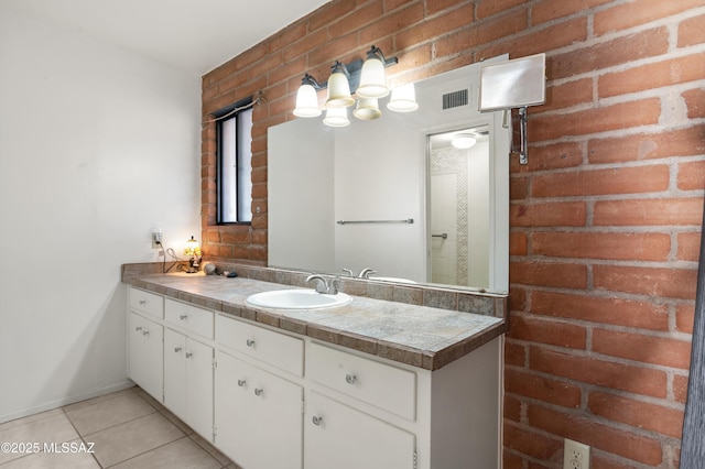 bathroom featuring vanity, tile patterned floors, and brick wall