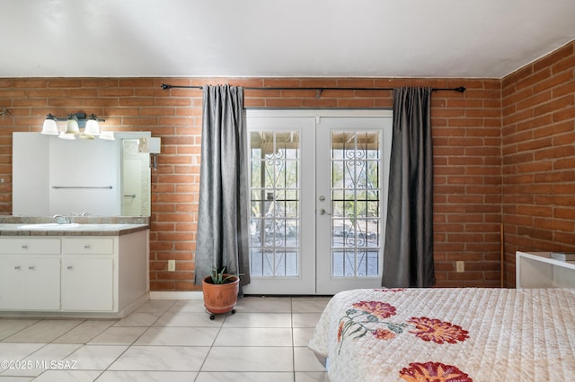 tiled bedroom featuring access to exterior, sink, french doors, and brick wall