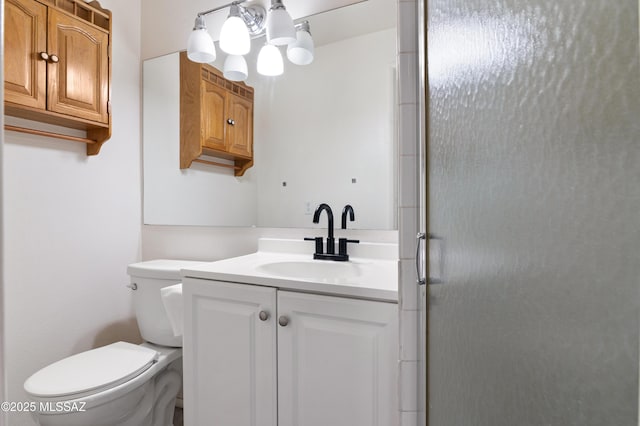 bathroom featuring vanity, a shower with shower door, and toilet