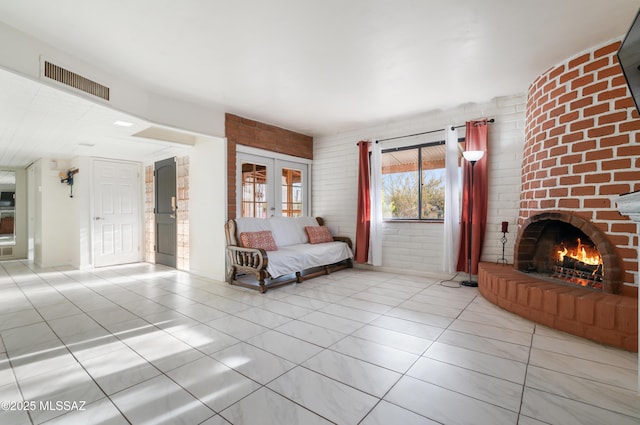 unfurnished living room with a fireplace, french doors, brick wall, and light tile patterned flooring