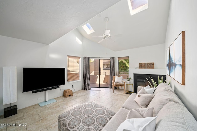 living room with ceiling fan, a skylight, and high vaulted ceiling