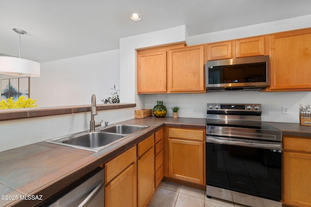 kitchen featuring sink, light tile patterned floors, hanging light fixtures, and appliances with stainless steel finishes