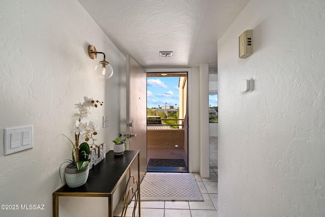 doorway to outside featuring light tile patterned floors and a textured ceiling