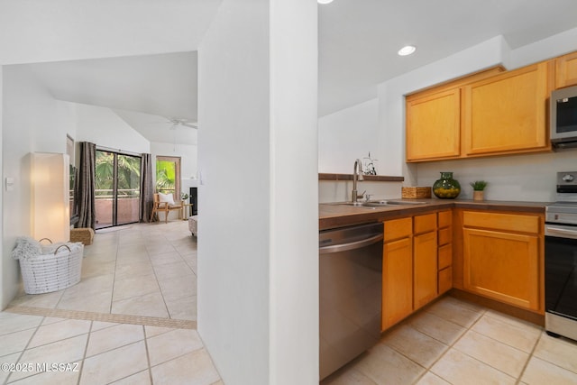 kitchen with sink, light tile patterned floors, ceiling fan, stainless steel appliances, and vaulted ceiling