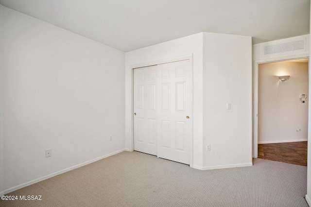 unfurnished bedroom featuring light colored carpet and a closet