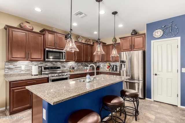 kitchen featuring decorative light fixtures, sink, a kitchen breakfast bar, a kitchen island with sink, and stainless steel appliances