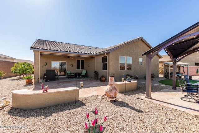 rear view of house featuring ceiling fan and a patio area