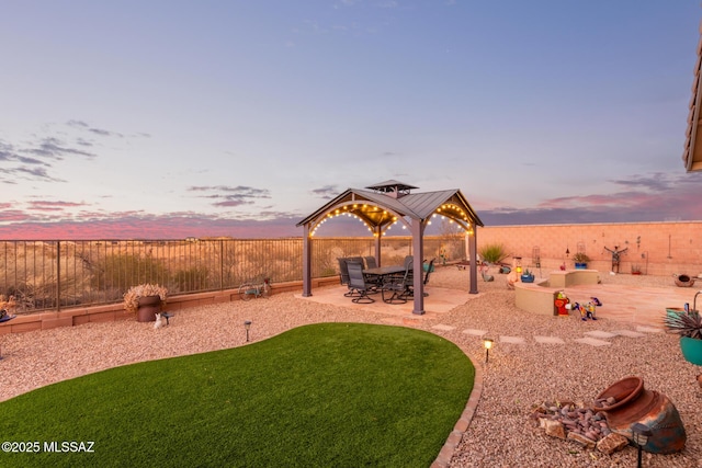 yard at dusk featuring a gazebo and a patio area