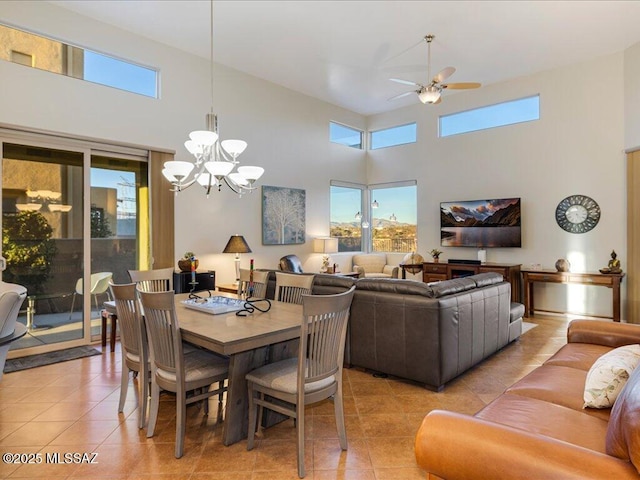 dining space featuring ceiling fan with notable chandelier, a towering ceiling, and light tile patterned floors