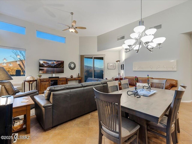 dining space with light tile patterned flooring, a towering ceiling, and ceiling fan with notable chandelier