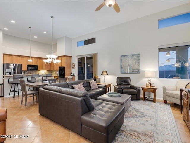 tiled living room featuring a towering ceiling and ceiling fan with notable chandelier